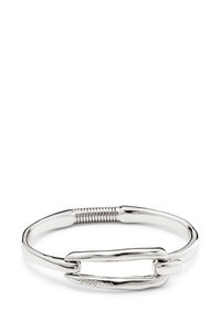 Pulsera de plata que presenta una forma ovalada alargada y lisa, con una sección texturizada en espiral y un cierre que se asemeja a un clip de papel.