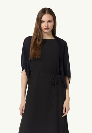 Marineblauer Schal-Kardigan mit kurzen Ärmeln, leichtem Stoff, offener Vorderseite, darüber getragen über einem schwarzen Kleid mit gebundenem Taillendetail.