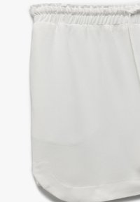 Hvide shorts lavet af letvægtsstof med elastisk talje. Slidsen har en afrundet kant, og teksturen ser glat ud.
