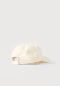 Εκρού βαμβακερό καπέλο μπέιζμπολ με ρυθμιζόμενο λουράκι και μεταλλική πόρπη, εμφανιζόμενο από πίσω πάνω σε λευκή επιφάνεια.