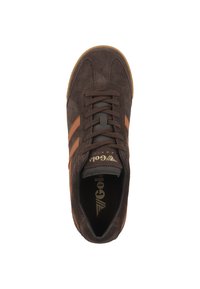 Sneaker in suede marrone con due strisce arancioni, punta tonda e lacci. Presenta una suola in gomma e un logo dorato sulla linguetta.
