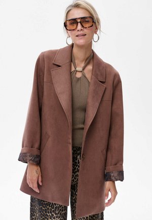 Brauner, strukturierter Blazer mit lockerer Passform, der mit Spitzenbesätzen an den Bündchen versehen ist. Kombiniert mit einem figurbetonten, neutralen Oberteil und einer Hose mit Leopardenmuster.