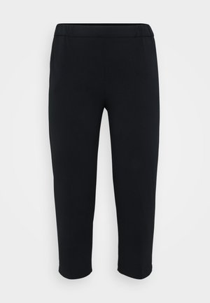 Sorte, slim-fit, ankellange bukser med elastisk liv på en ensfarvet lys bakgrunn.