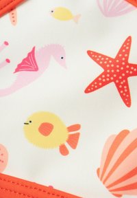 Schwimmloden mit einem weißen Hintergrund und bunten Meeresmustern: gelbe Fische, rosa Seepferdchen, rote Seesterne und rosa Muscheln. Orangefarbener Saum.