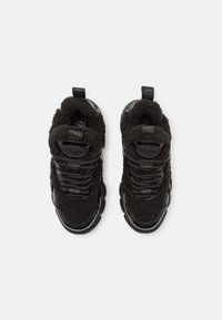 Zwarte sneakers met een gestructureerde, pluizige bovenkant, gladde lakaccenten en contrasterende zwarte veters. Dikke rubberen zool en pull-tab.