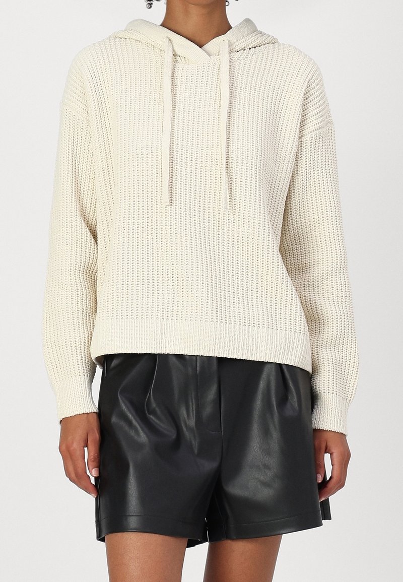 Felpa con cappuccio in maglia color crema con motivo testurizzato, coulisse sul cappuccio e orlo a coste. Abbinata a pantaloncini larghi in pelle nera.