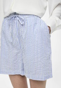 Shorts légers à rayures bleues et blanches avec une taille élastique et un cordon de serrage. Le tissu a une texture douce et une coupe décontractée.