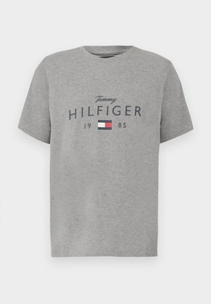 Szary podkoszulek z okrągłym dekoltem z napisem "Tommy Hilfiger 1985" i prostokątnym logo w kolorach czerwonym, białym i niebieskim na piersi.