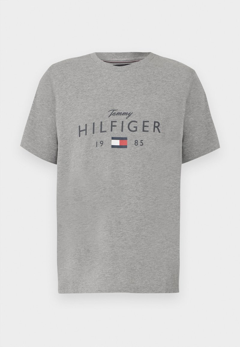 Grå T-shirt med rund hals med teksten "Tommy Hilfiger 1985" og et rektangulært logo i rød, hvid og blå på brystet.