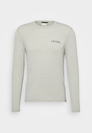Camisa de manga larga gris claro hecha de una tela suave. Presenta un cuello redondo y un pequeño logotipo "LE COL" en el lado izquierdo del pecho.