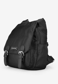 Mochila negra de nailon con cierre tipo solapa, múltiples compartimentos con cremallera y acentos en tono plateado. Cuenta con correas ajustables.