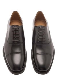 Chaussures habillées en cuir noir avec une finition lisse, un embout arrondi et un design subtil de bout dur. Elles disposent de six œillets pour les lacets et de détails surpiqués.