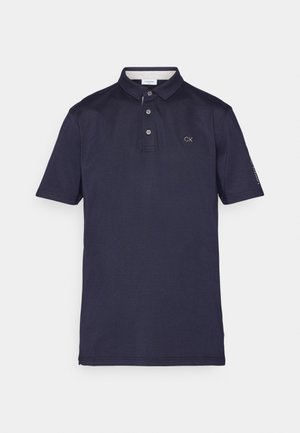 Tumesinine polo särk, mis on valmistatud puuvillast, kaeluse, kolme nupuga avatuse ja rinnas brodeeritud CK logoga. Lühikesed varrukad.