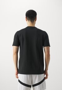 Svart kortärmad t-shirt i mjukt tyg, med rundad halsringning. Har en slät yta och en avslappnad passform. Bakvy.