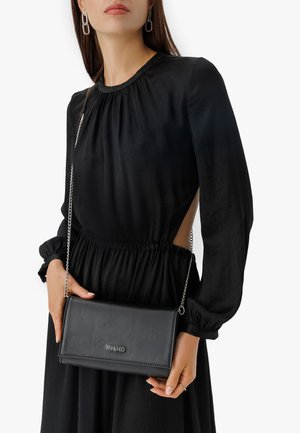 Borsa a tracolla in ecopelle nera con tracolla in catena argentata, forma rettangolare e cuciture sottili. Logo impresso sulla parte anteriore.