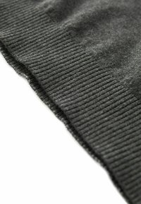 Grauer Strickpullover mit ribbeltem Saum, der eine weiche Textur und ein glattes Finish aufweist. Der Rand ist leicht gewellt.