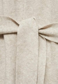 Tessuto lavorato a maglia beige con una texture morbida presenta una cintura annodata, creando una forma definita. Sfumature sottili di colore in tutto il tessuto.