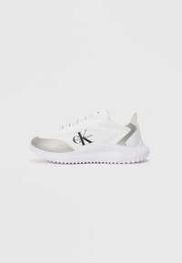 Λευκά αθλητικά παπούτσια με ασημένια λεπτομέρεια, λείο υλικό και ελαστική σόλα. Διαθέτουν ένα έντονο μαύρο λογότυπο στο πλάι και κορδόνια.