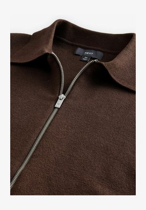 Brun strikket zip-up trøje med krave, der har en sølvfarvet lynlås og en struktureret stof. Etiket læser "NEXT," størrelse M.