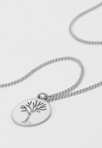Collier en argent avec un pendentif rond au design d'arbre découpé. La chaîne est finement maillée, mettant en valeur une finition polie.