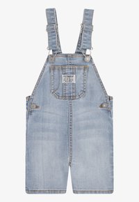 Ljusblå denimoverall med justerbara axelremmar, framficka och knappstängning; har en blekt struktur och synlig sömnad.