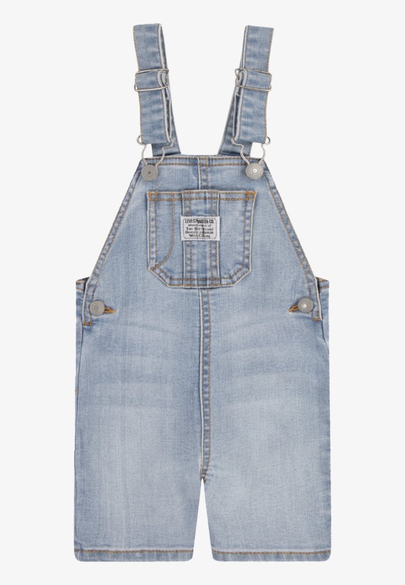 Ljusblå denimoverall med justerbara axelremmar, framficka och knappstängning; har en blekt struktur och synlig sömnad.