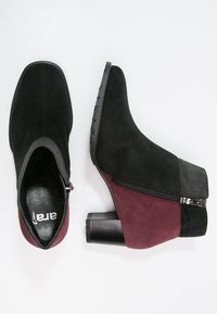 Stivaletti alla caviglia in suede nero e bordeaux con tacco a blocco, dotati di zip laterale e texture contrastante nel tacco e nella parte superiore.