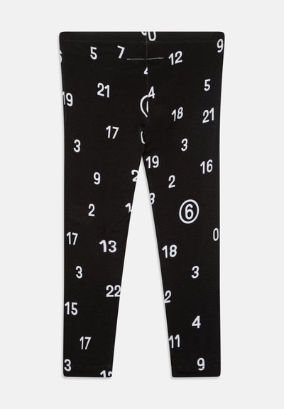 Sorte leggings med et gjentatt mønster av hvite tall, som varierer i størrelse, med en merkbar sirkel rundt tallet "6."