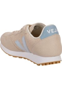 Béžové tenisky vyrobené z mesh a semišového materiálu. Svetlomodré akcenty. Biela gumová podrážka s textúrovaným gripom. Logo "VEJA" na päte.