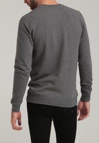 Sweat-shirt gris à manches longues en tissu doux mélangé coton, avec col rond et poignets côtelés, cintr é au corps.