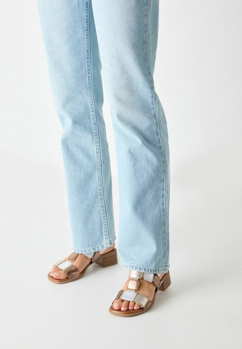 Bruna och silver blockklackade sandaler med fyrkantiga utskärningar, bärs med ljusblå raka jeans, vilket framhäver skornas design detaljer.