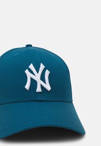 Teal baseball-lippu, jossa on kaareva lippa ja etuosassa suuri valkoinen brodeerattu "NY"-logo sekä teksturoitu kangas.
