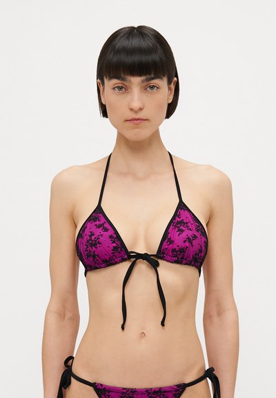 Haut de bikini triangle en violet avec des motifs floraux noirs, doté de liens et de bordures noirs. Design à col halter, couverture minimale, texture de tissu douce.