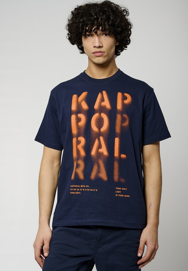 T-shirt en coton bleu marine avec du texte sprayé orange. Doté d'un col rond, de manches courtes et d'une taille droite. Le texte comprend le logo de la marque et des slogans.