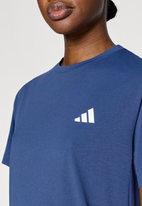 Μπλε σκούρο μπλουζάκι με κοντά μανίκια, στρογγυλή λαιμόκοψη, κατασκευασμένο από απαλό ύφασμα. Διαθέτει λευκό γραφικό σχέδιο στην αριστερή πλευρά του στήθους.