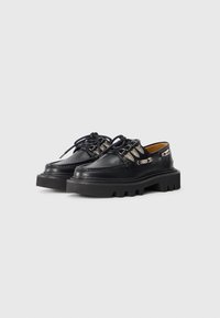 Chaussures en cuir noir avec des semelles en caoutchouc épaisses, dotées d'accents en argent et d'un design classique à lacets. Des détails texturés ajoutent un intérêt visuel.