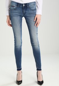 Jeans ajustados de color azul con un acabado desgastado, que cuentan con un cierre de gancho y cremallera, cinco bolsillos, costuras en contraste y una silueta estrecha.