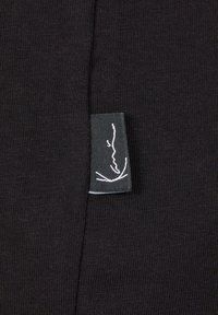 Black fabric with a ribbed texture features a label with a white minimalist line drawing on a dark background.