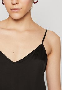 Black camisole with thin adjustable straps and a V-neck design. The fabric is smooth, with a slight sheen and minimal stitching details.