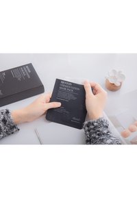 Benton Fermentation Mask Pack, confezione nera con testo bianco, tenuta in mano; maglione texturizzato; lo sfondo include elementi decorativi.