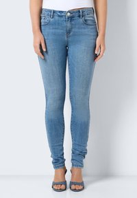Smal denimjeans i ljusblått, med en slät yta, klassisk femficksdesign, knapp- och dragkedjestängning, samt subtila blekningar.