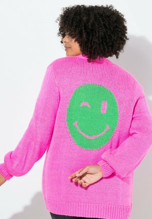 Dicker Strickpullover in leuchtendem Pink mit langen Ärmeln. Auf der Rückseite befindet sich ein großes grünes Smiley-Gesicht-Graphic. Texturiert, lässige Passform.