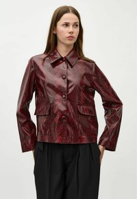 Röd ormtryckt läderjacka med krage, framknäppning med knappar och två fickor fram. Har en kort design och mjuk textur.
