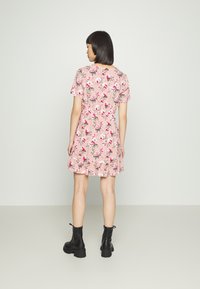 Vestido floral rosa com mangas curtas, bainha com volantes e cintura ajustada. Usado com botins pretos de atacador.