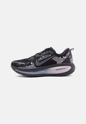 Chaussure de course Nike noire et grise avec un motif à petites taches blanches, logo swoosh gris et semelle épaisse amortie portant l'inscription « ZoomX » sur fond blanc.