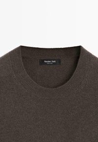 Brun stickad tröja med rund halsringning. Tyget verkar mjukt, med ribbad detaljering vid kragen. Etiketten visar "Massimo Dutti, Made in China."
