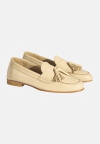 Beige Leder Slipper mit weicher Textur, ausgestattet mit einer Fransen-Applikation an der Vorderseite und einem niedrigen, flachen Holzabsatz.