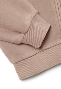 Sudadera rosa claro con puños y dobladillo acanalados. La tela es suave y tiene una textura delicada, con detalles de costura mínimos.