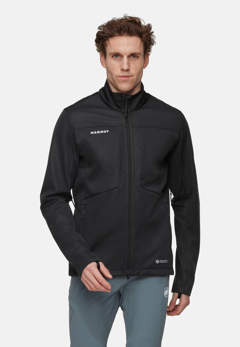Zwarte softshell jas met ritssluiting aan de voorkant, hoge kraag, twee zijzakken en logo op de borst. Glad, rekbaar materiaal, aansluitend ontwerp.