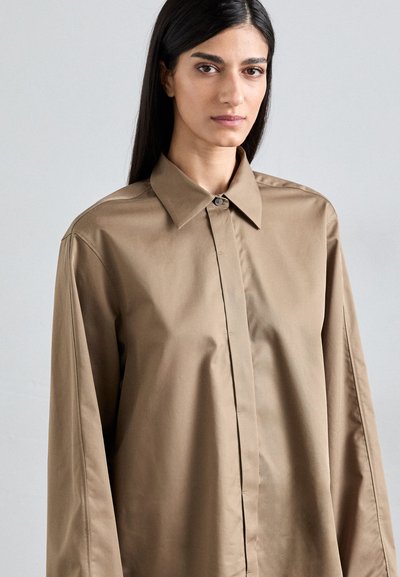 Light brown button-up shirt with a classic collar, long sleeves, and smooth texture; features a subtle sheen and clean lines.